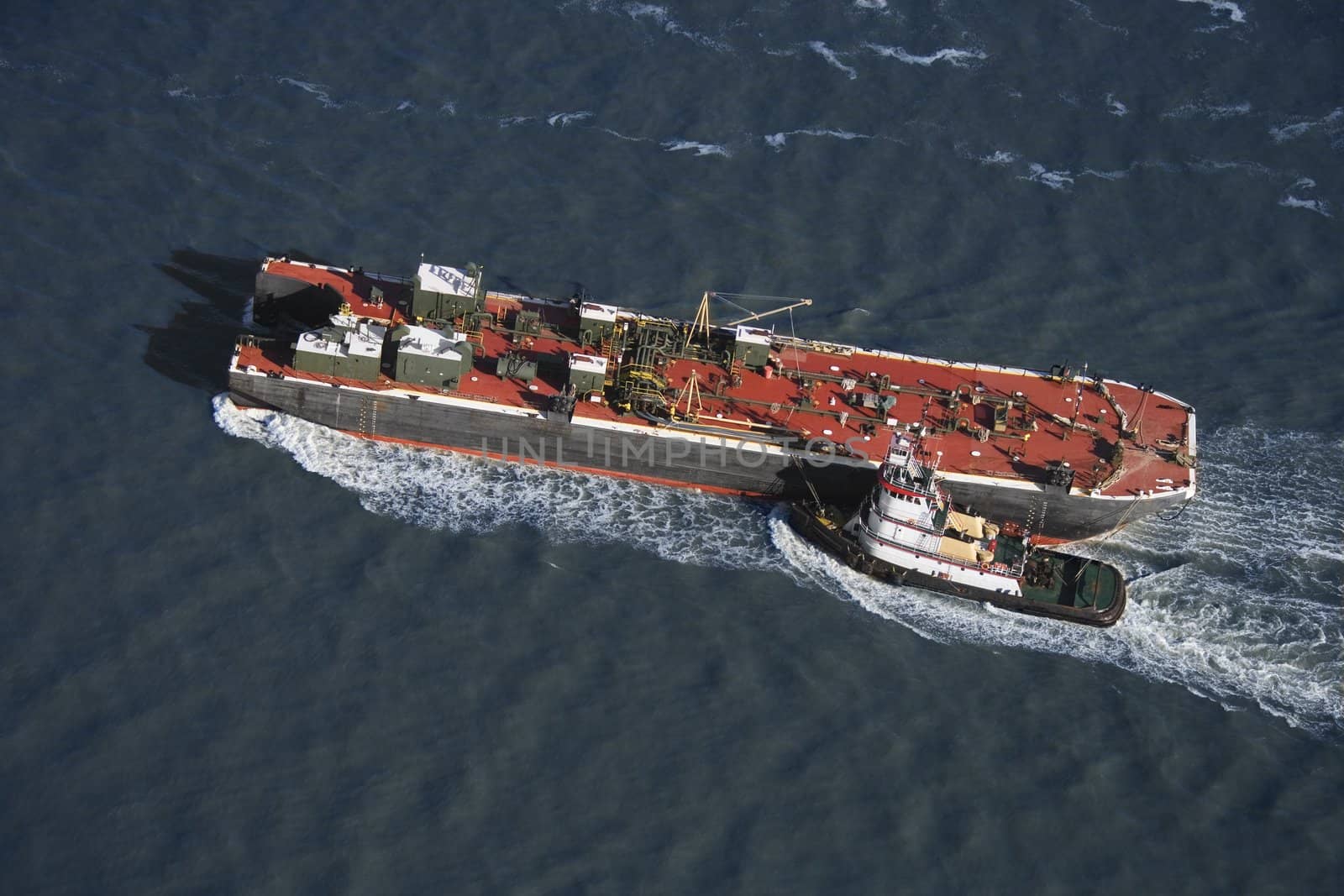 Aerial view of tugboat pushing tanker.