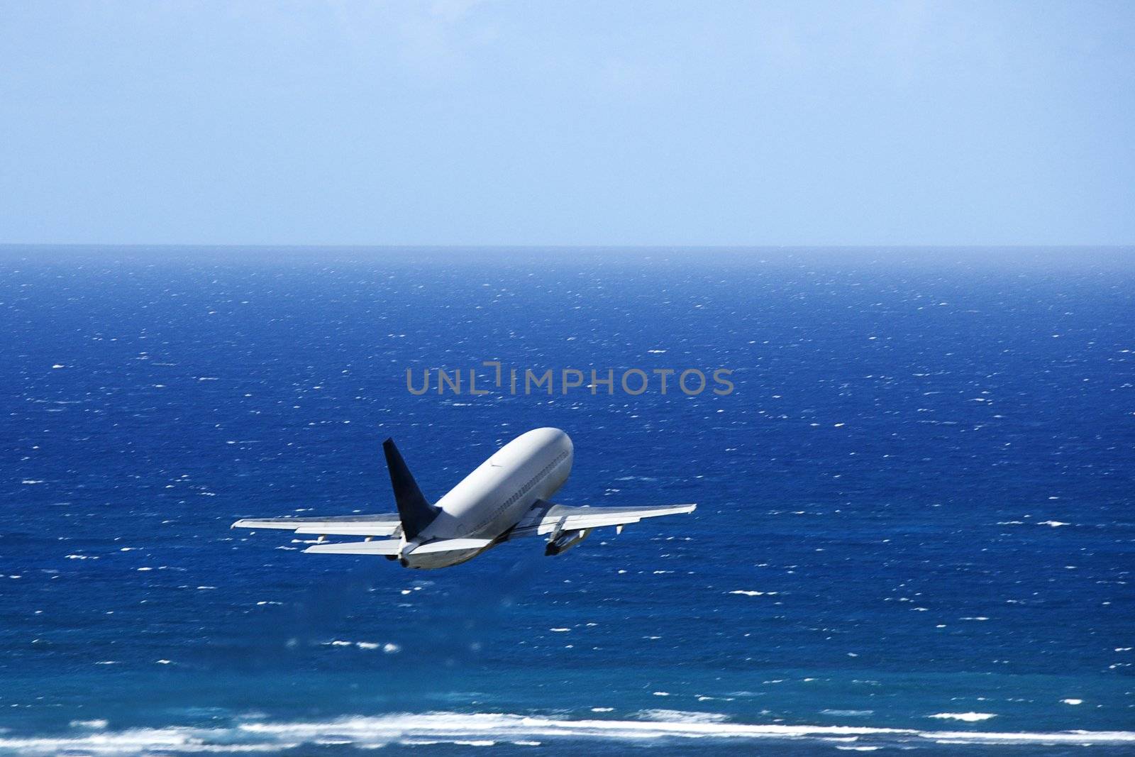 Passenger airplane taking off from airport headed over the Pacific ocean.