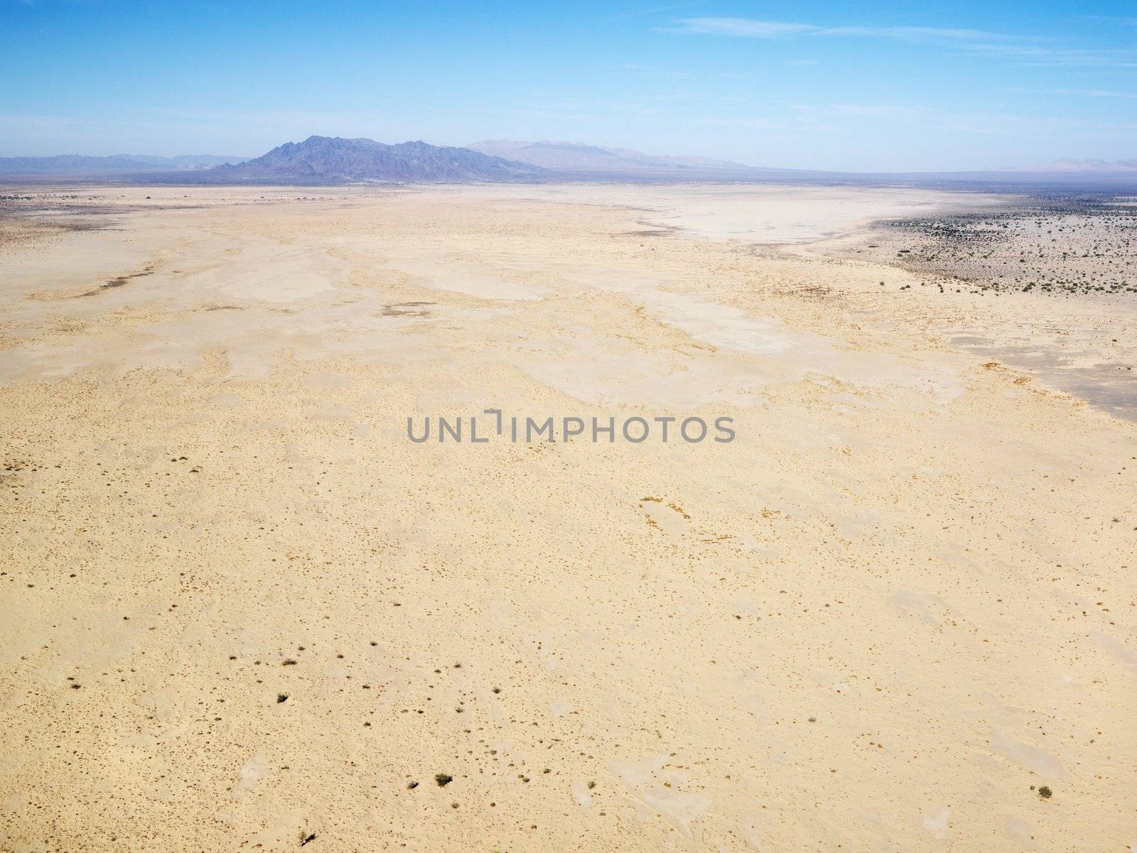 Aerial view of remote California desert with mountain range in background.