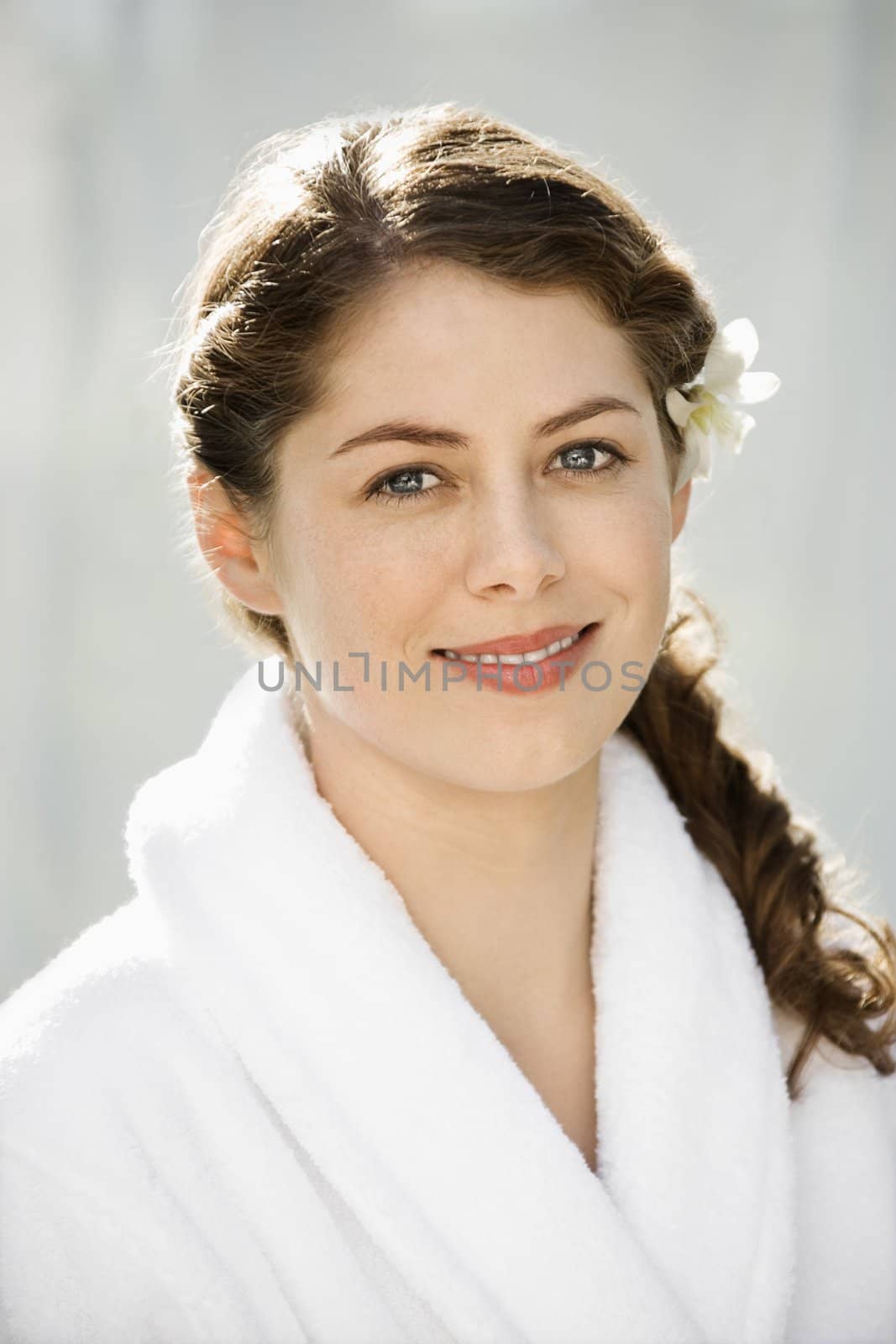 Pretty brunette Caucasian mid-adult woman wearing white robe smiling and viewer.