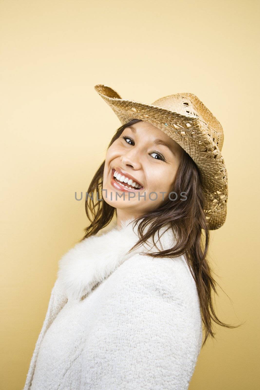 Young adult Caucasian woman wearing cowboy hat smiling at viewer.