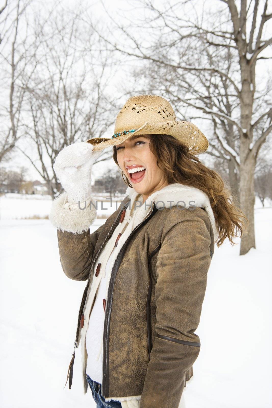 Woman tilting hat. by iofoto