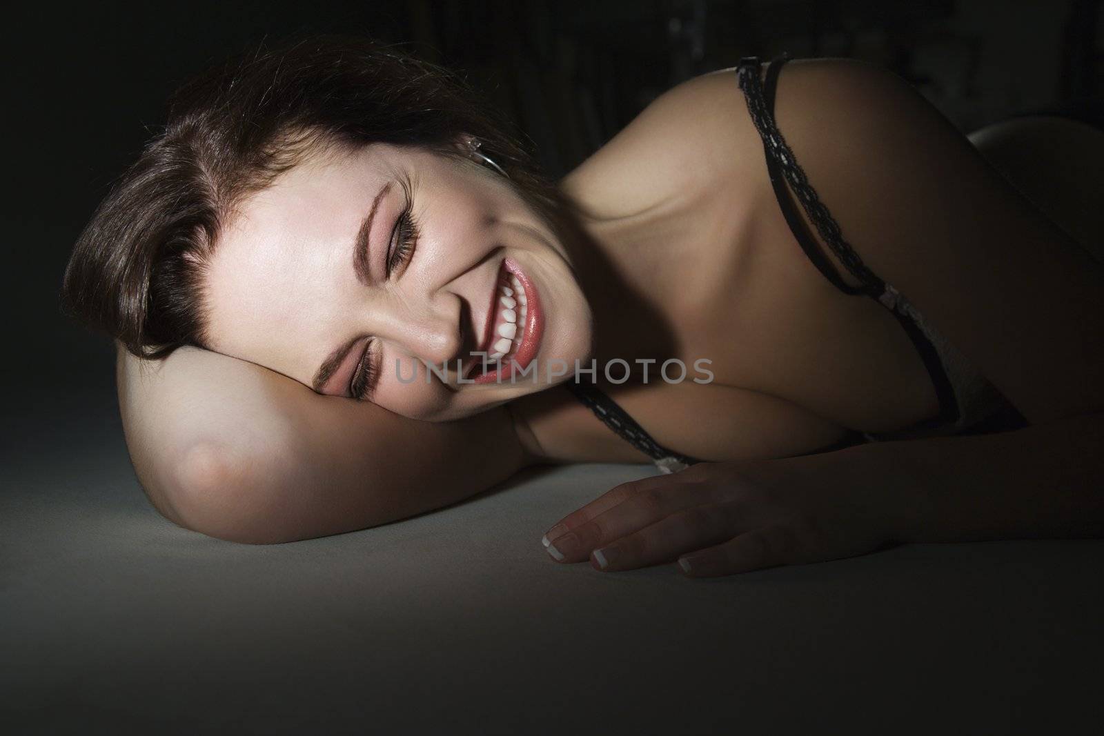 Sexy Caucasian woman in bra lying on floor and smiling.