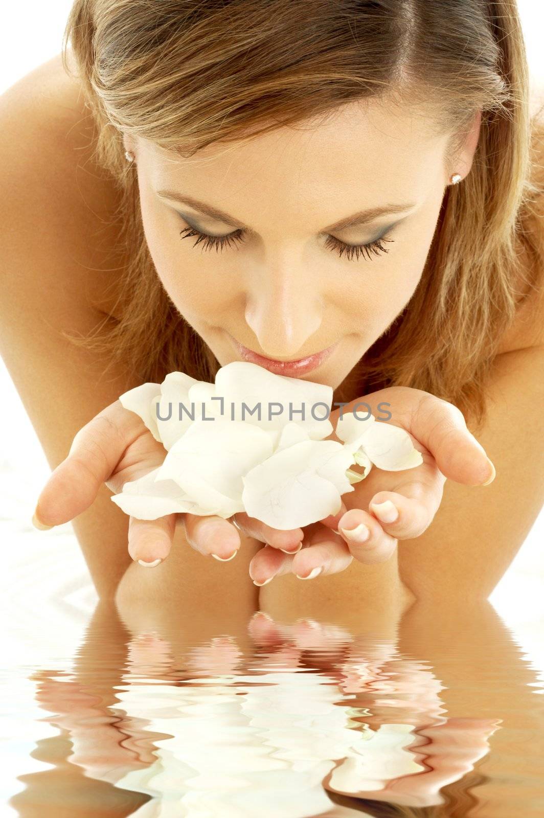 lovely woman in water smelling white rose petals