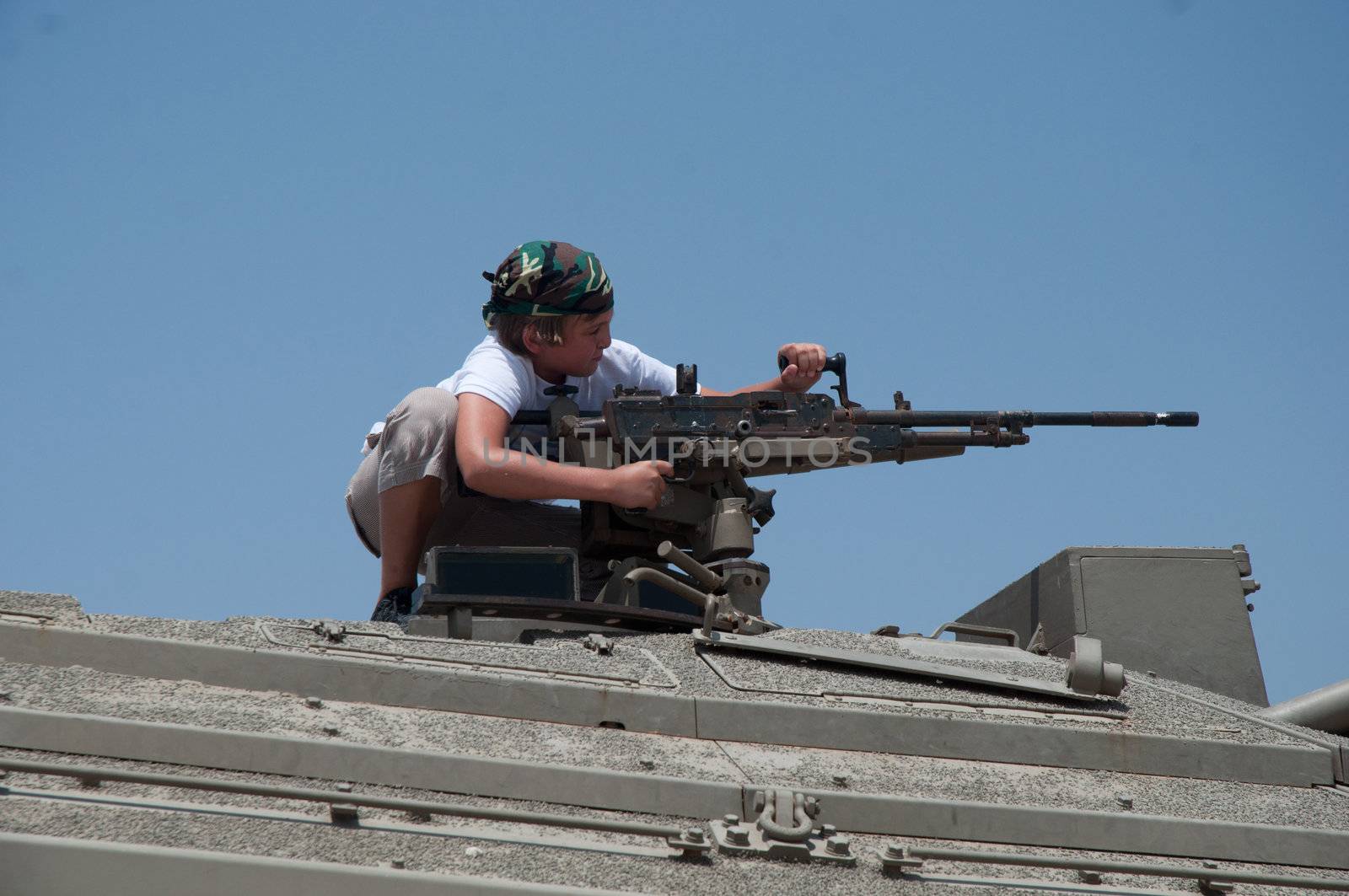 A boy playing with a machine gun mounted on top of the turret.