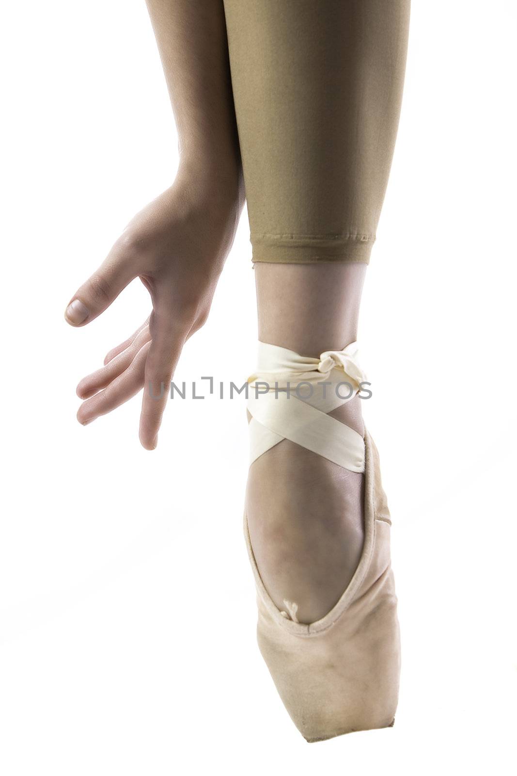 young Caucasian girl in ballet slippers standing on one pointed toe stretching hands to feet