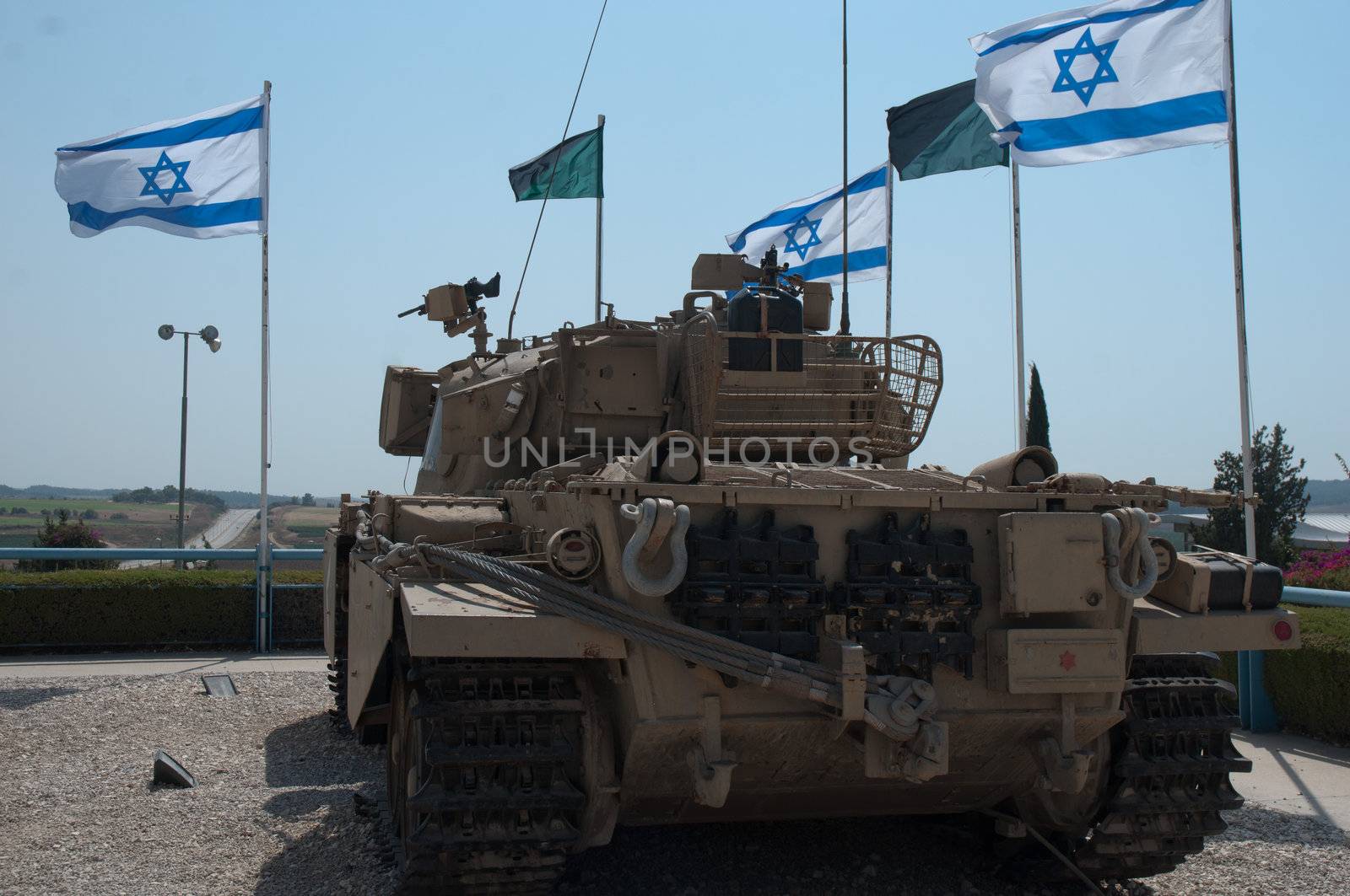 Old tank against the blue sky and white-blue flags of Israel. Israel, Latrun.