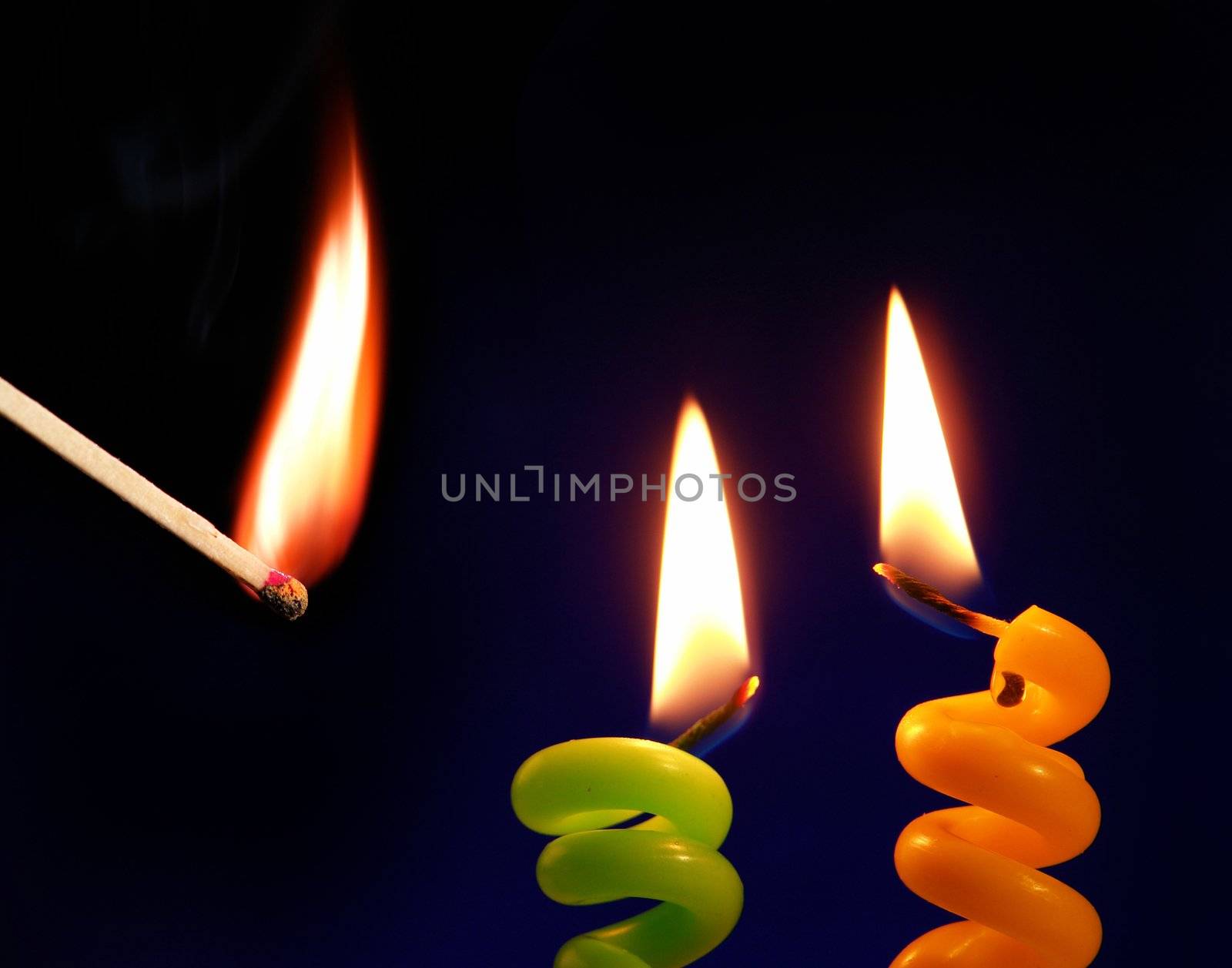 Candle and match on a black background                               