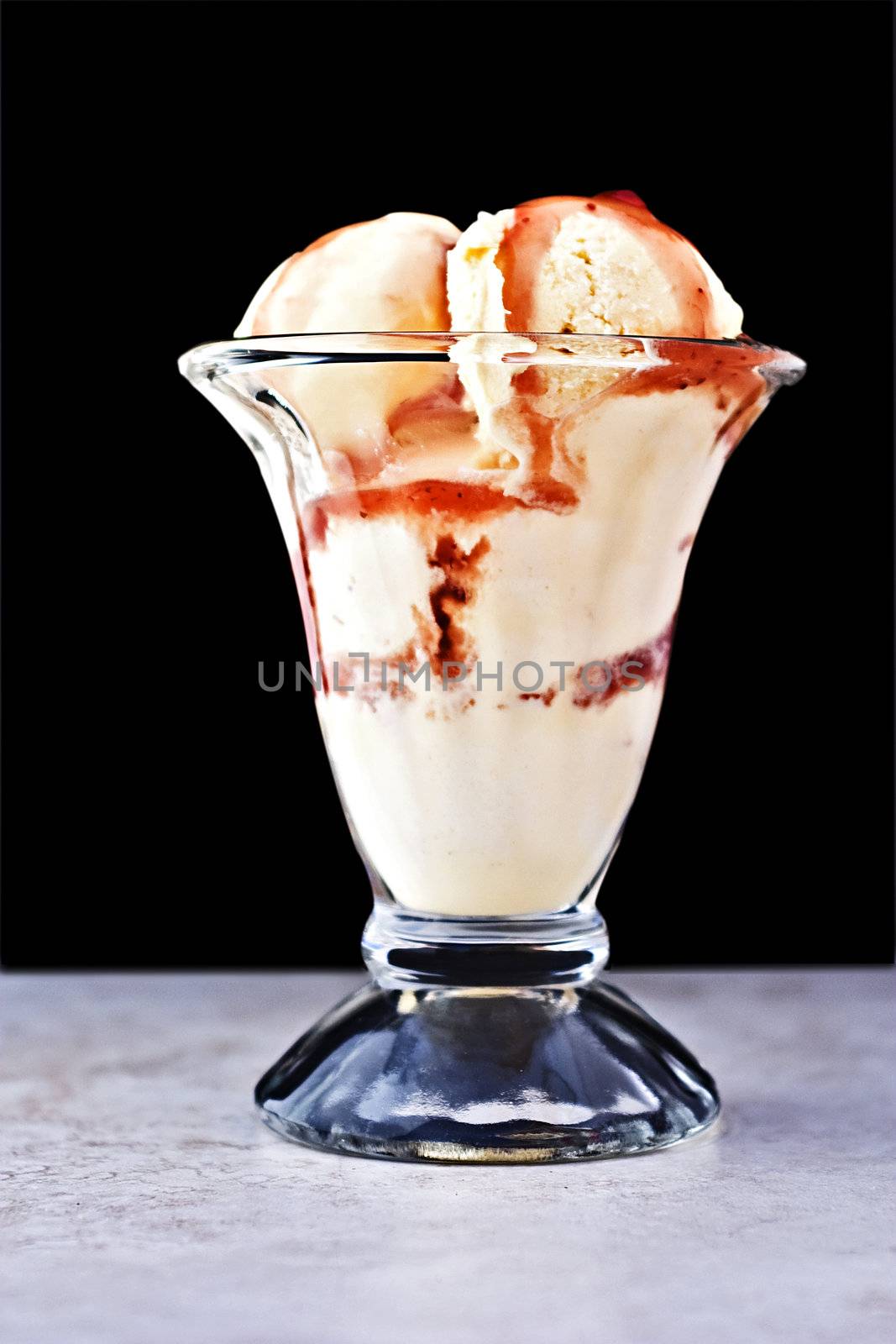 French vanilla ice cream with fruit sauce against a black background

