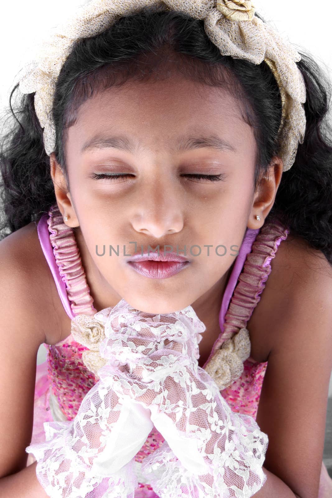 A portrait of a cute Indian girl saying a prayer, on white studio background.