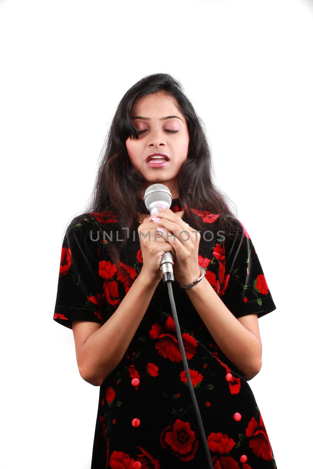 A devoted young Indian singer saying a prayer, on white studio background.