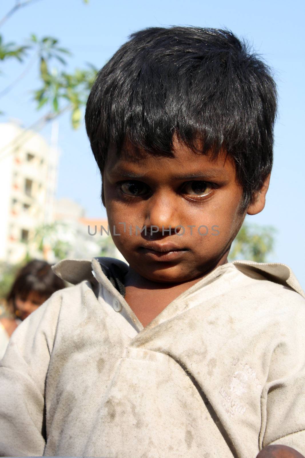 A portrait of a very poor kid from India with a shocked expression on his face.