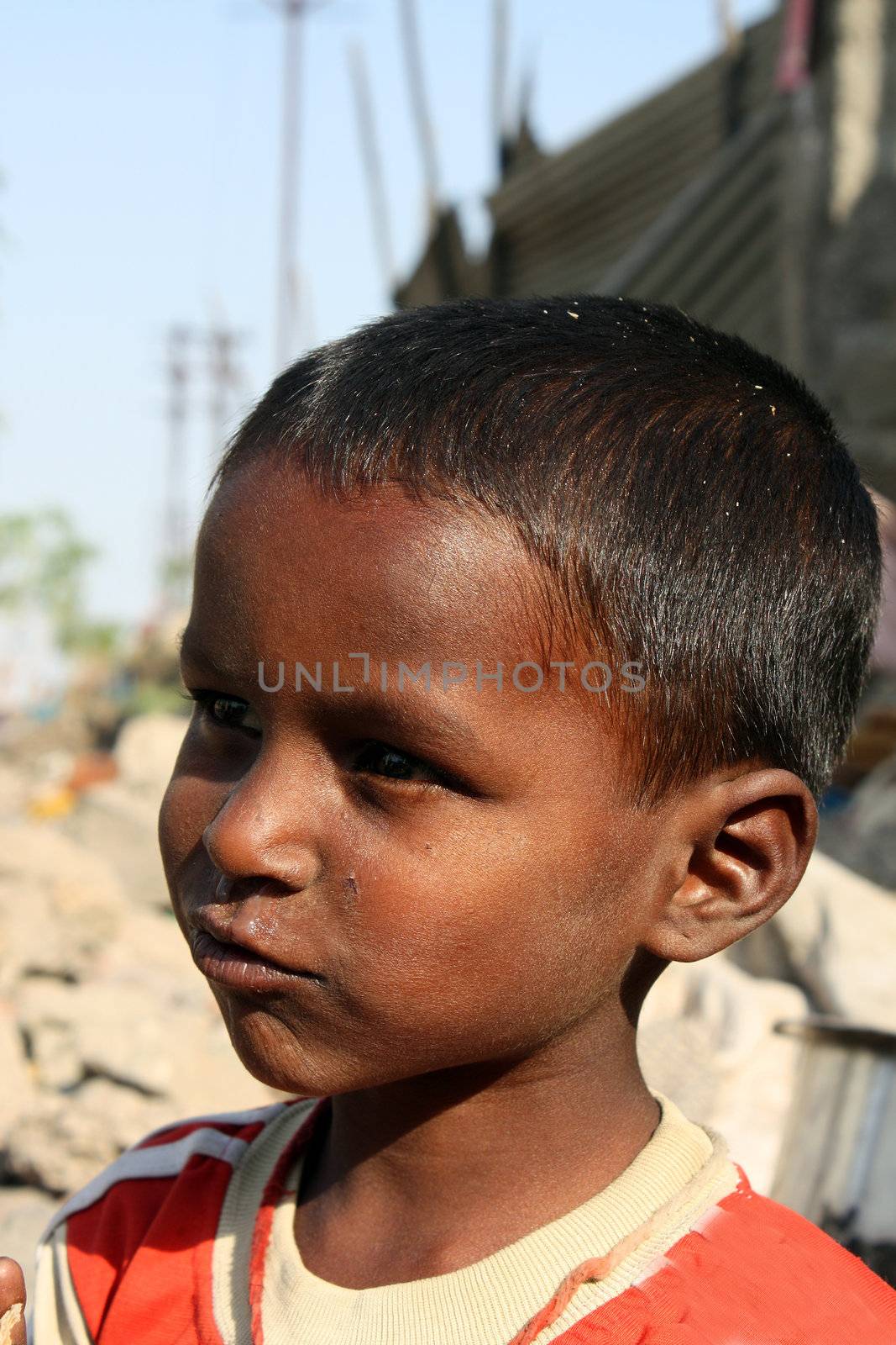 A portrait of a daydreaming poor beggar kid from India.