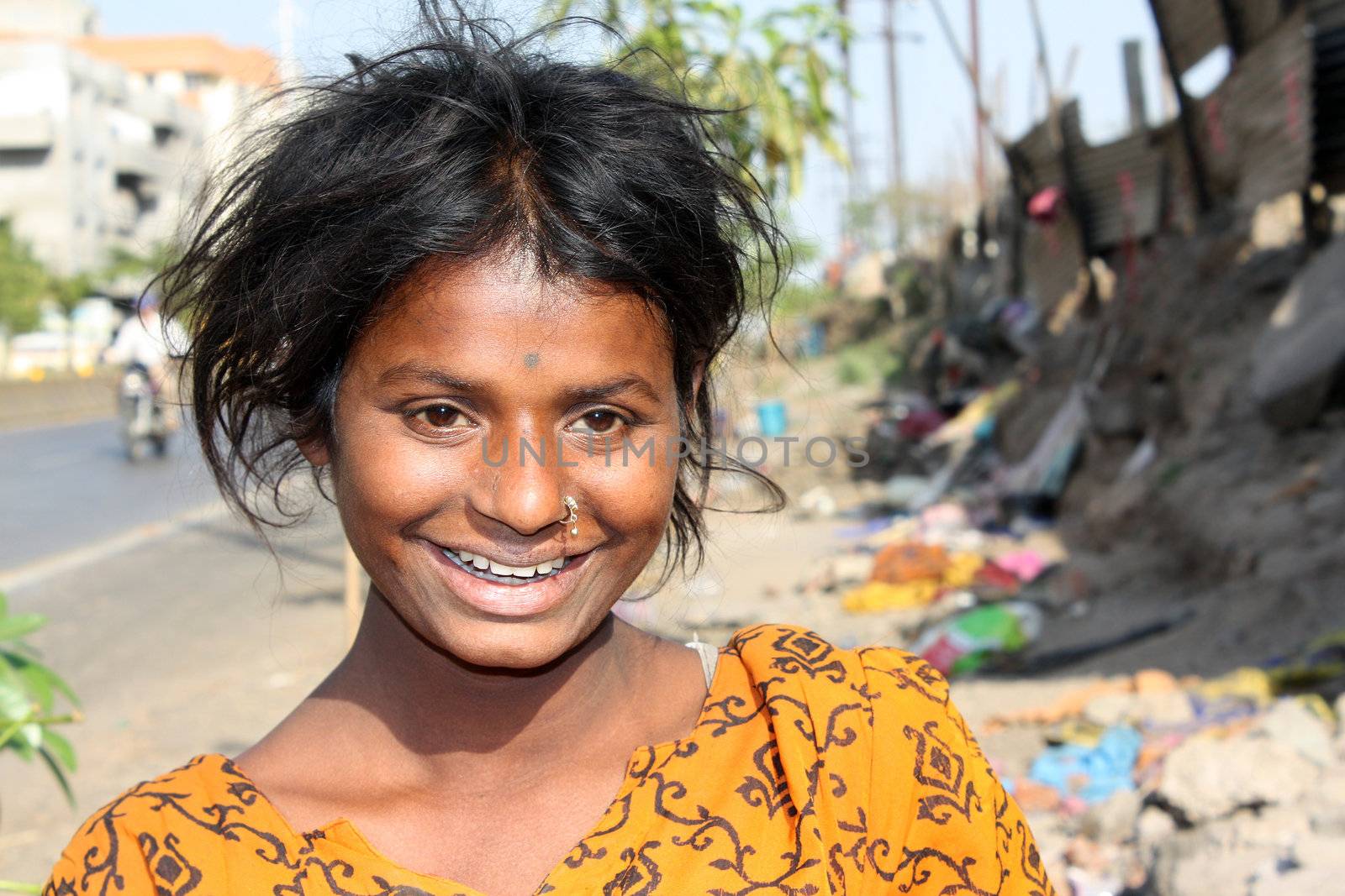 A portrait of a happily smiling poor Indian teenager, on the streetside.