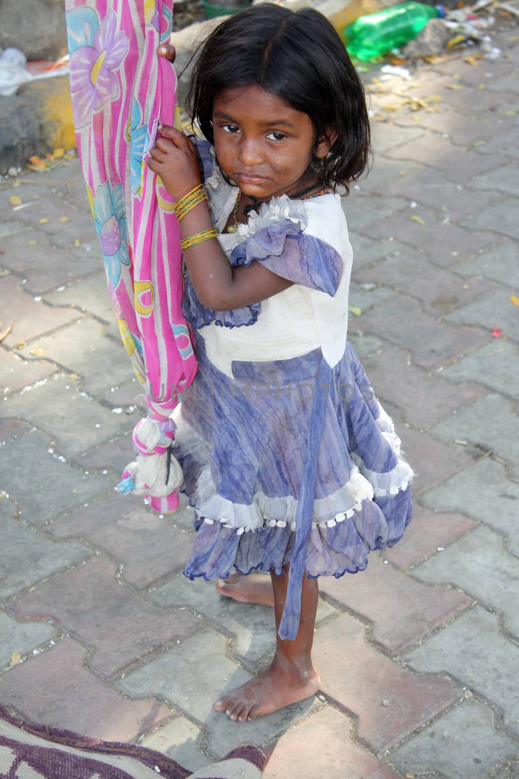 A sad poor girl having no one to play with, on an Indian street-side.