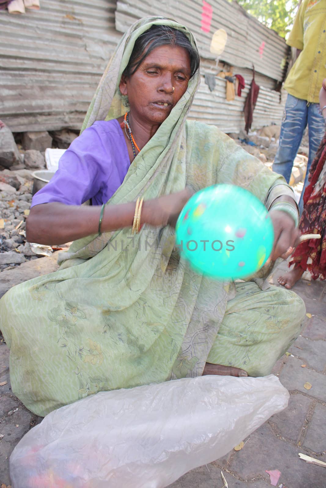 A poor old woman making balloons to make a living. An image in motion showing her tying a string on the balloon.