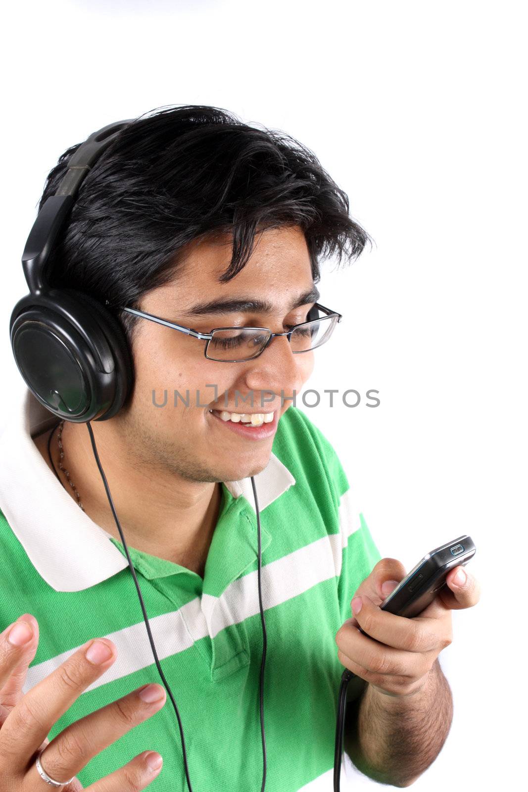 An Indian teenager listening to music on his headphones and a MP3 cellphone, on white studio background.