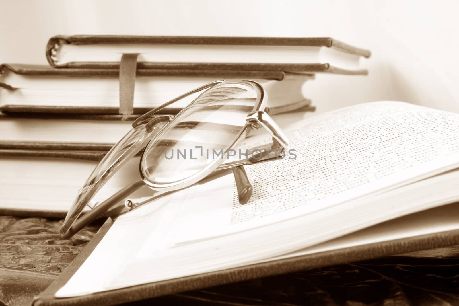 A vintage background of reading glasses kept on a book, in a library.