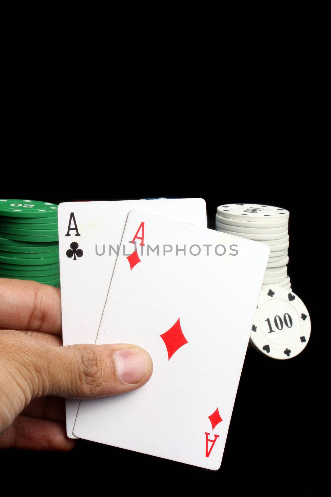 A great poker hand of two aces with casino chips in the backdrop, isolated on black studio background.