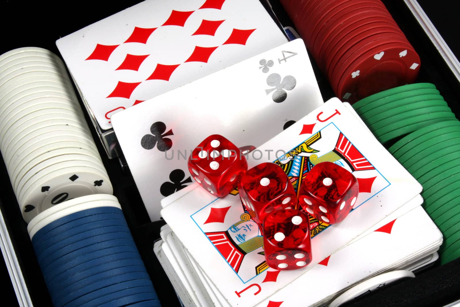 A closeup view of colorful casino chips, red dices and cards in a casino bag.