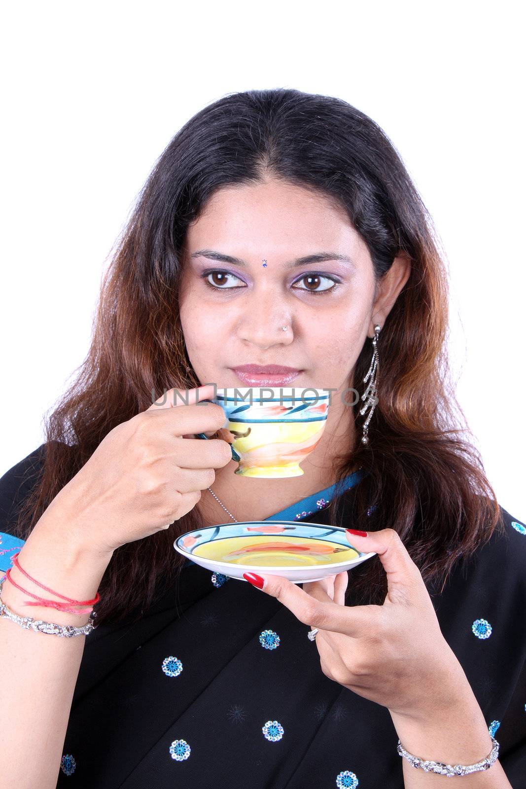 A portrait of a traditional Indian woman drinking tea / coffee.