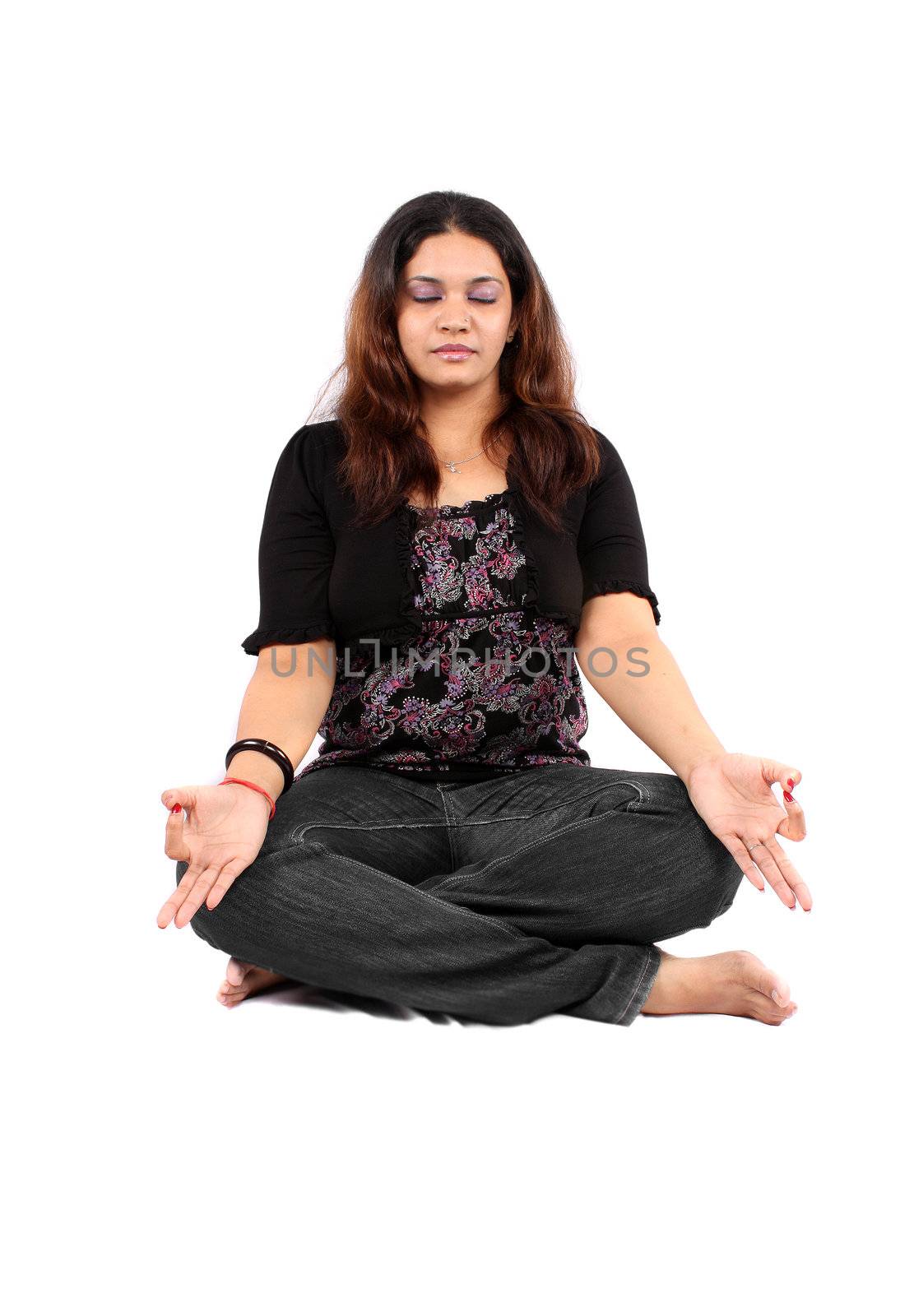 A young Indian teenage girl in meditation, on white background.