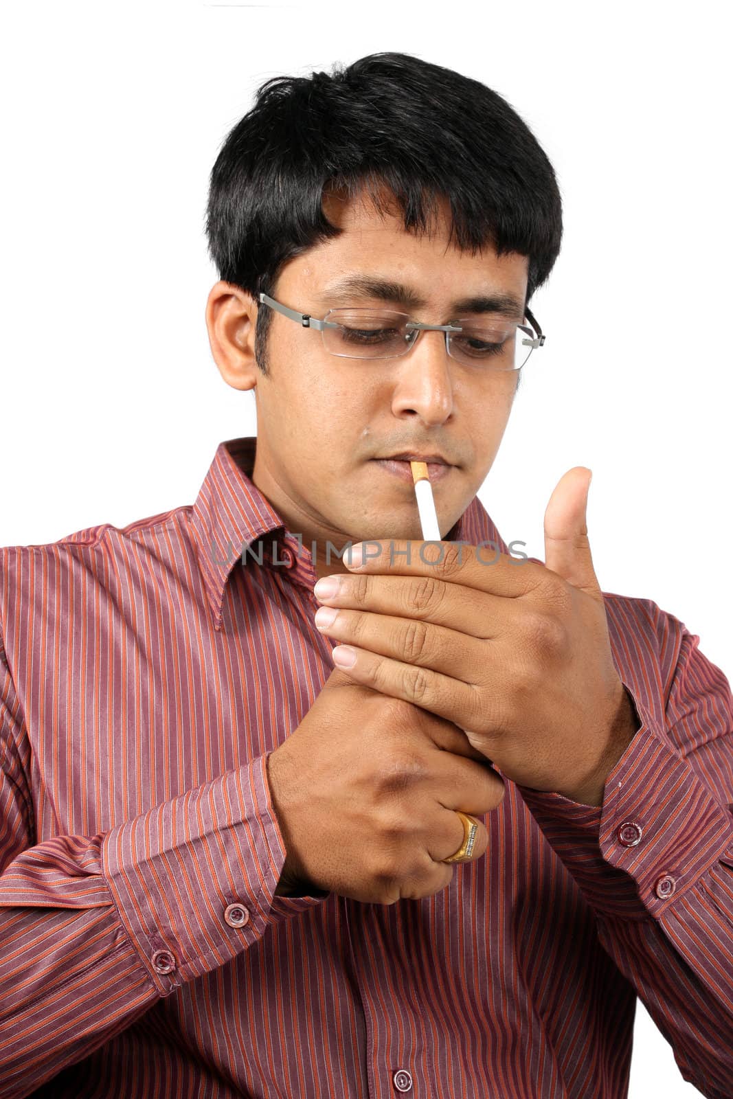 An Indian office executive lighting his cigarette during a break, on white studio background.