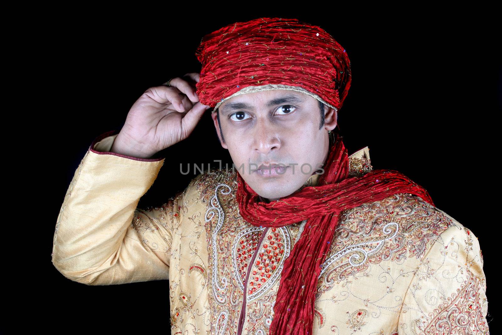 An Indian man wearing a traditional turban, on black studio background.