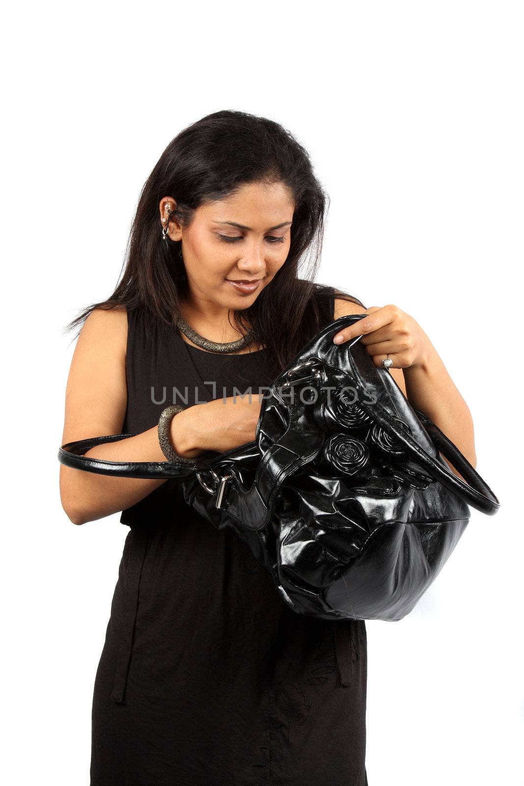 A beautiful Indian woman checking contents of her black handbag, on white studio background.