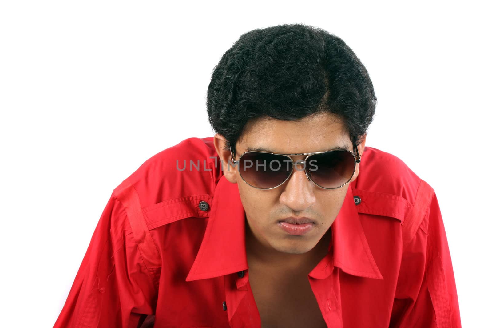 A portrait of a young Indian guy in red shirt and sunglasses, on white studio background.