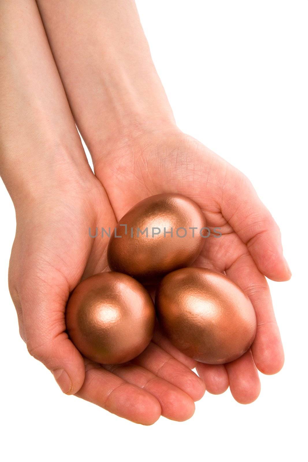 Female hands hold three gold Easter eggs on a white background
