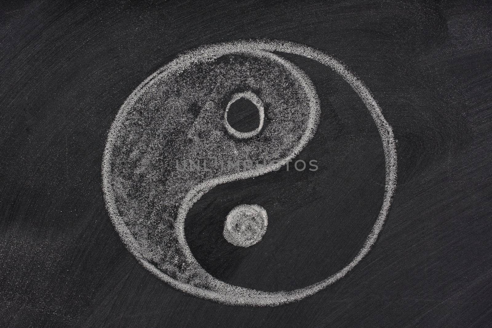 yin and yang symbol sketched with white chalk on a blackboard with eraser smudges