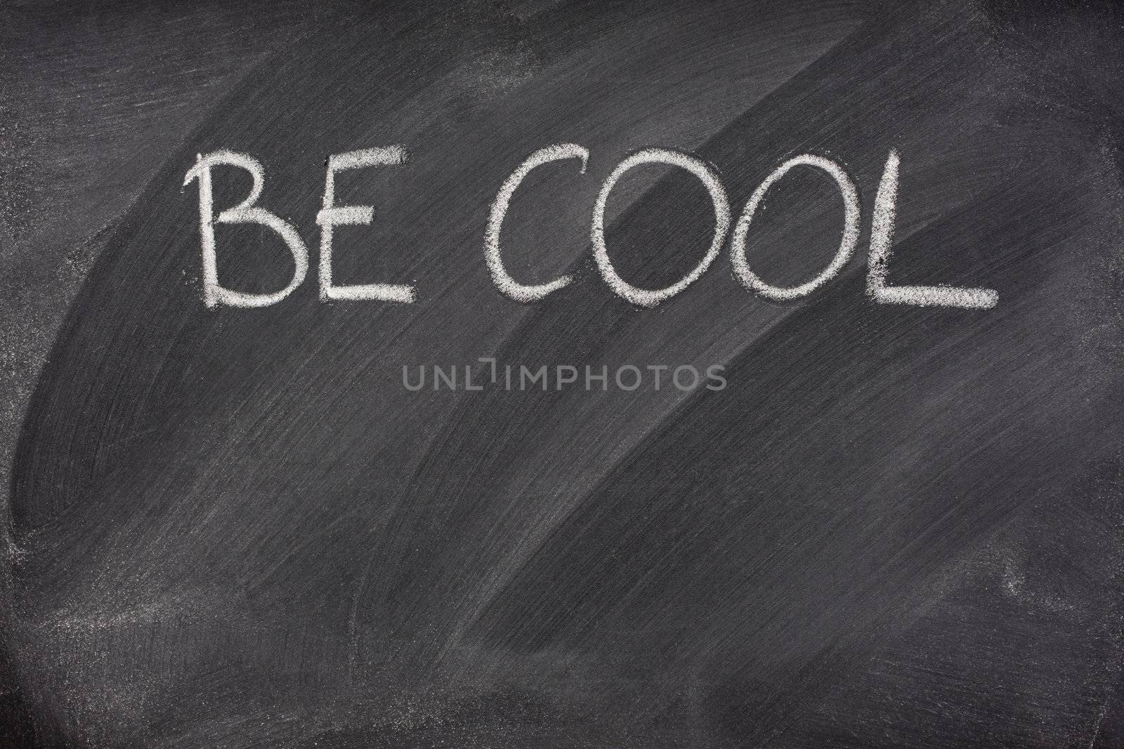 Be Cool phrase handwritten with white chalk on a blackboard with eraser smudges