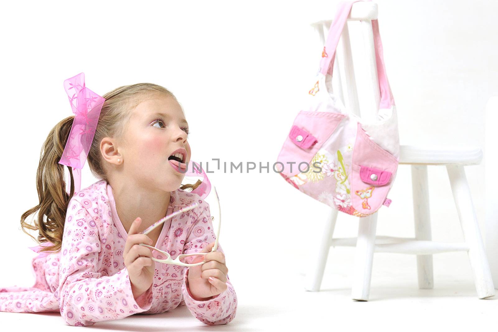 Pretty girl with sunglasses, laying on the floor with white chair and pink hand bag by Ansunette