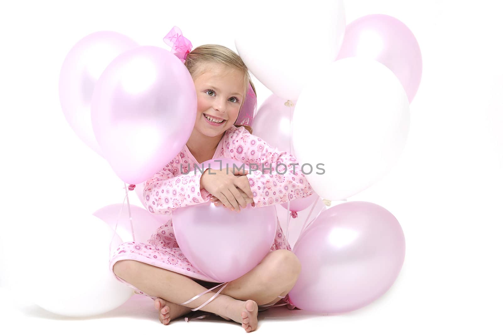 a pretty young blond girl sitting between pink and white balloons