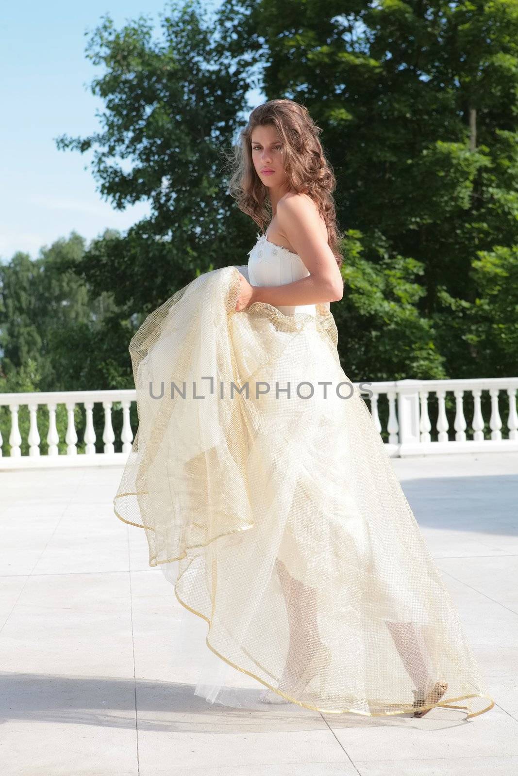 beautiful girl in wedding gown on background of the snow-white banisters