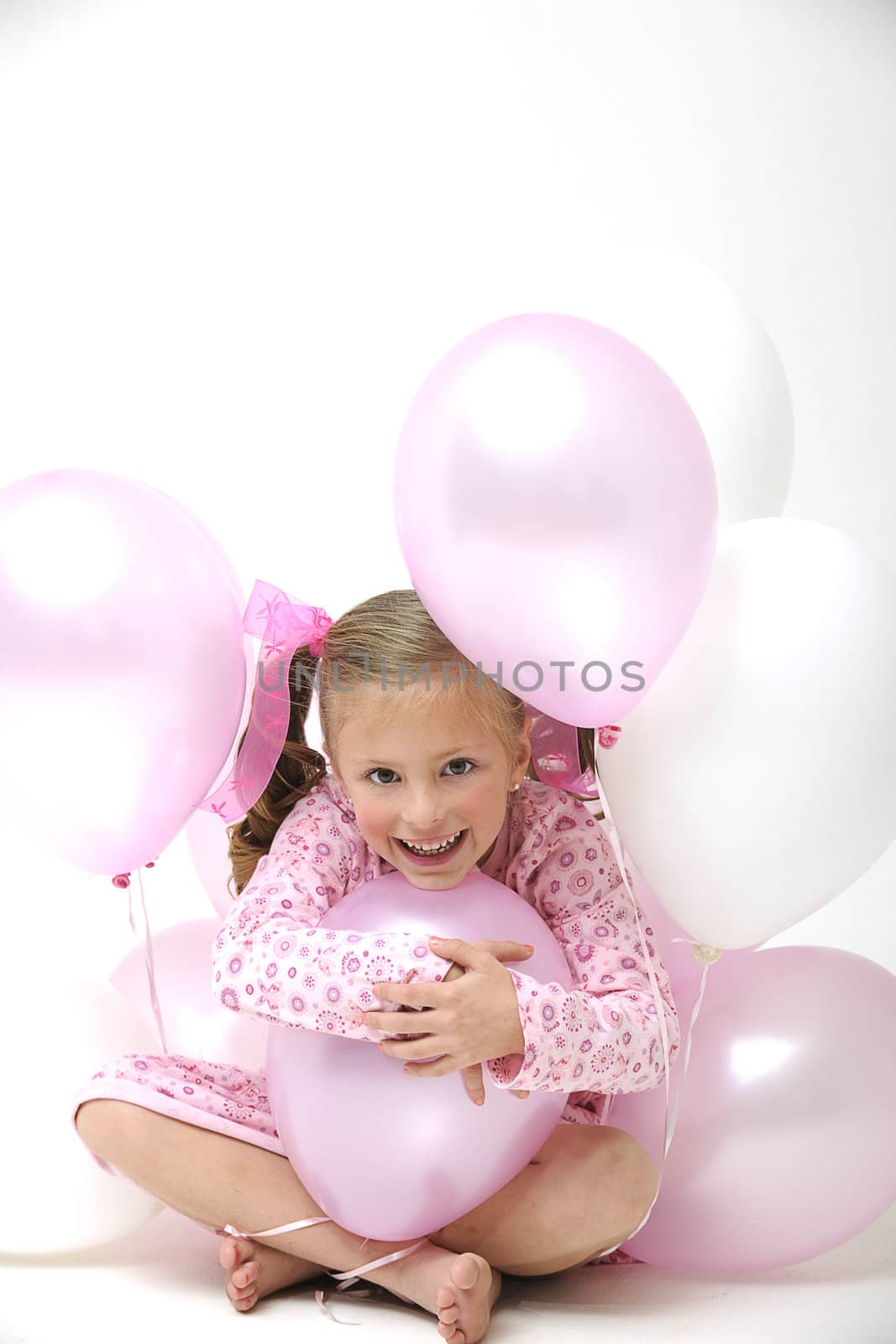 a pretty young blond girl sitting between pink and white balloons