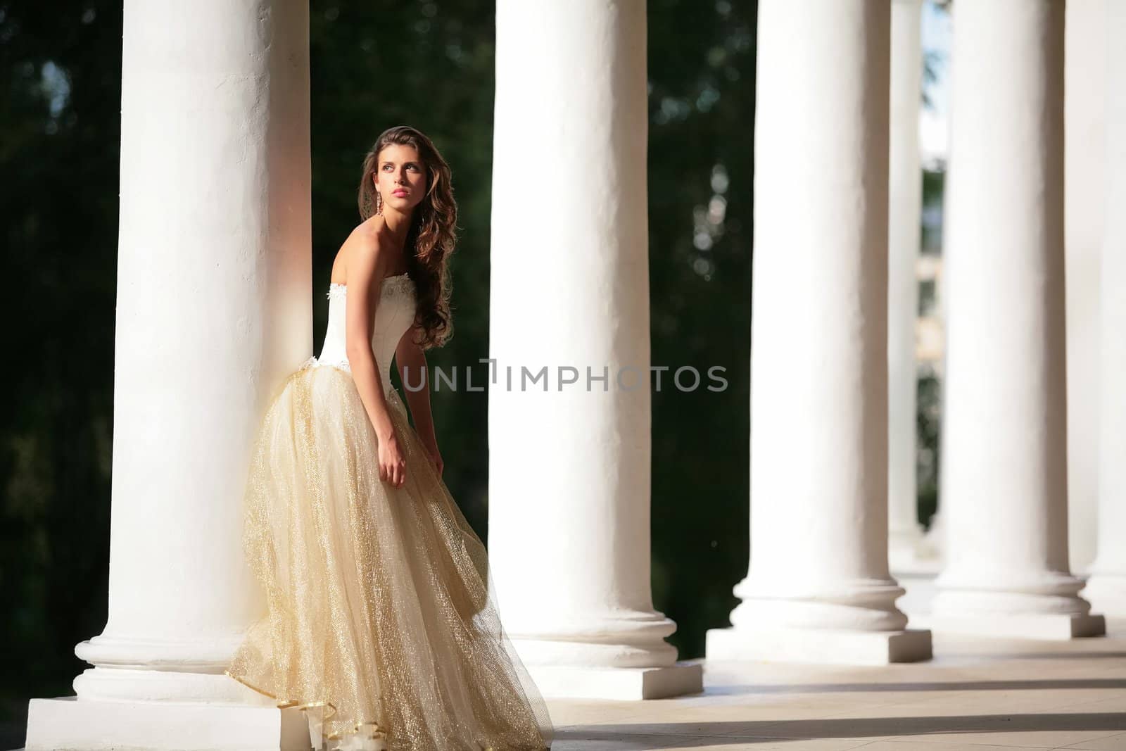 colonnade of the old-time building and beautiful girl in white-golden gown of the bride