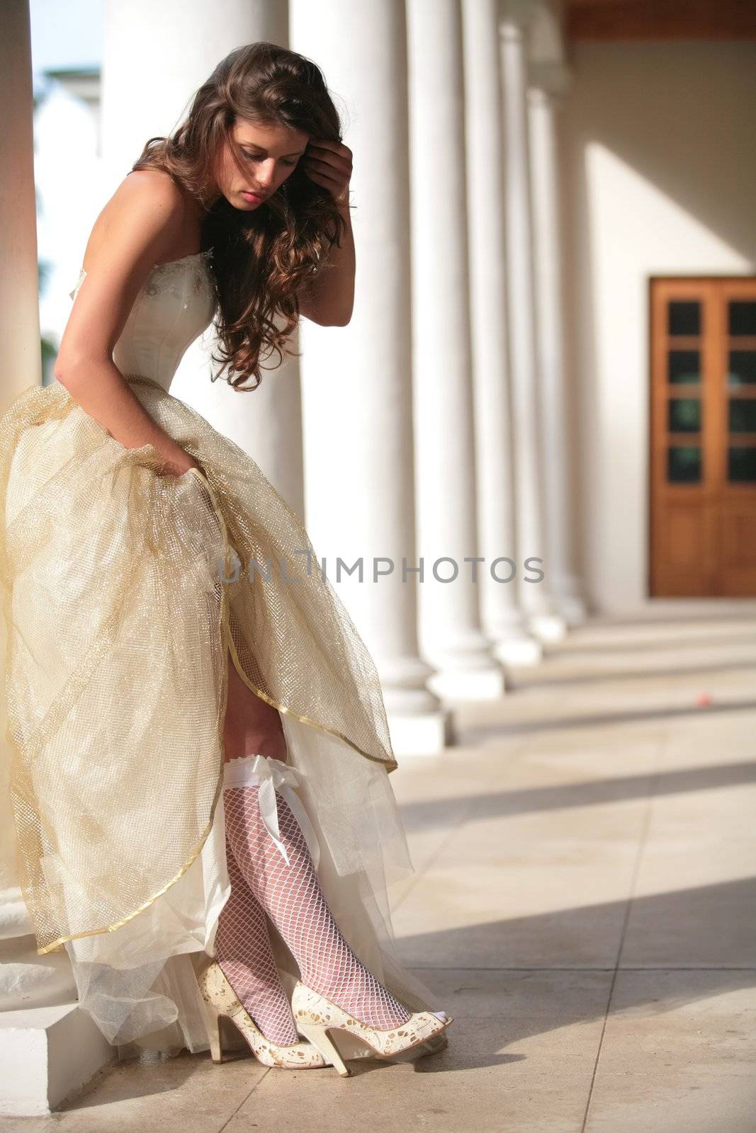 beautiful girl in gown of the bride corrects white golfs with bow