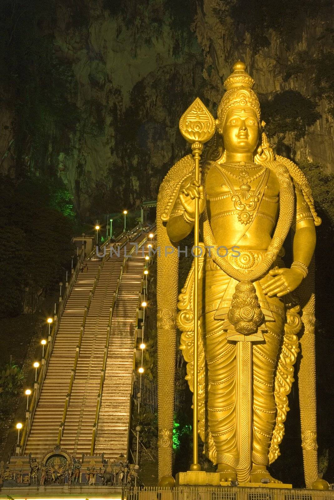 Night image of Batu Caves in Malaysia. In the foreground is the world's tallest (42.7 meters) statue of Lord Muruga, a Hindu deity. Also seen here is the stairway to the caves.