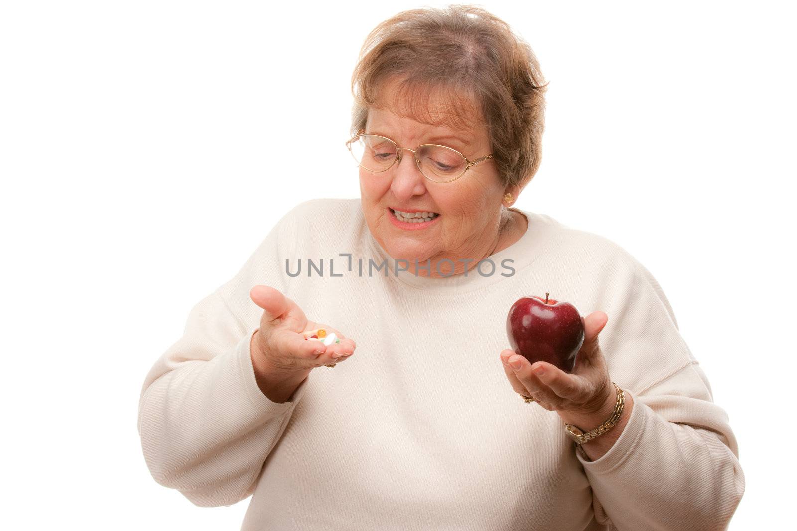 Confused Senior Woman Holding Apple and Vitamins Isolated on a White Background.