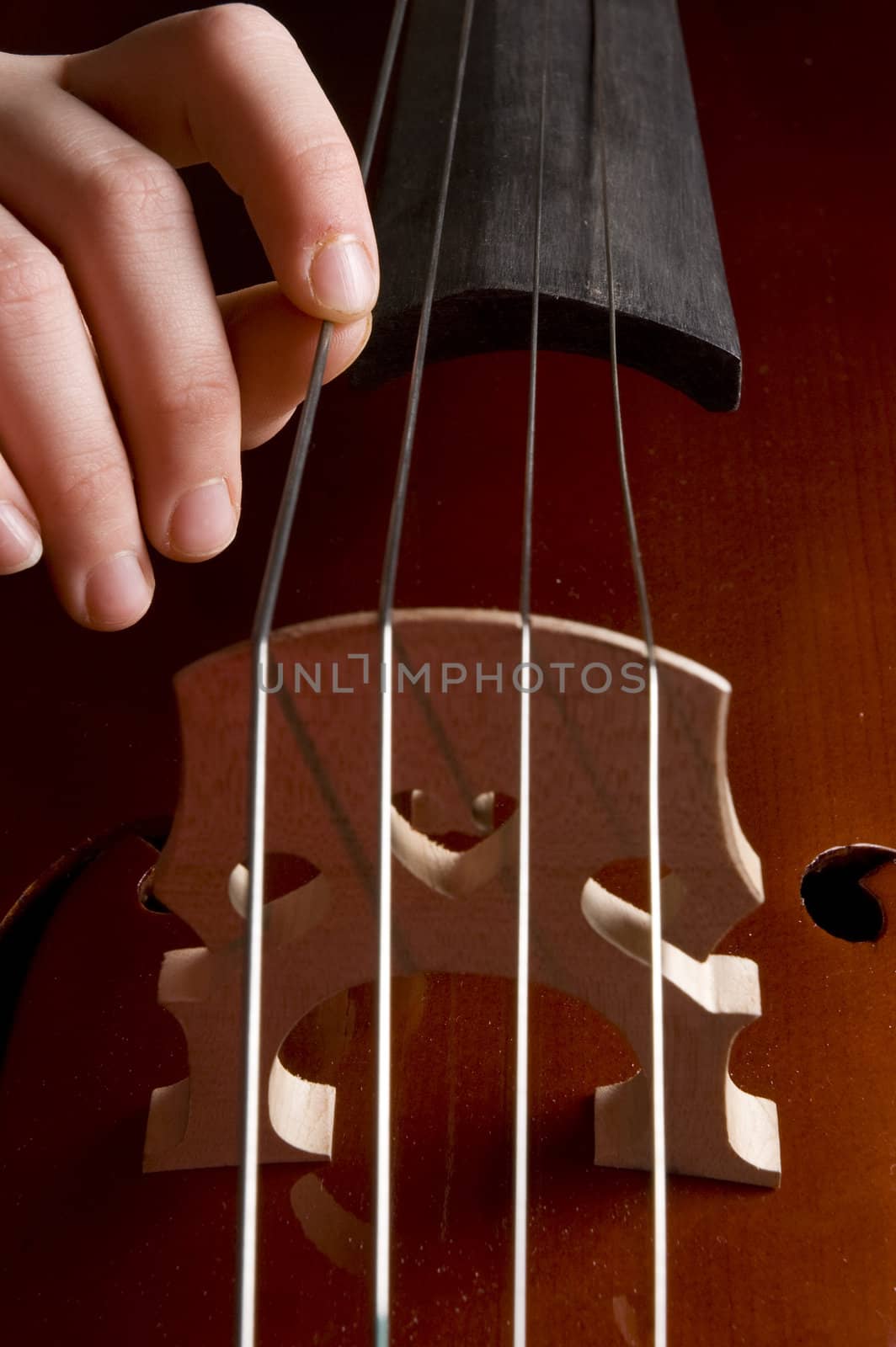 close up of a childhand is playing the cello