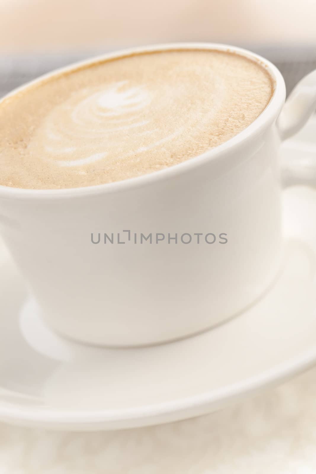 Coffee (latte) with milk foam on light brown table