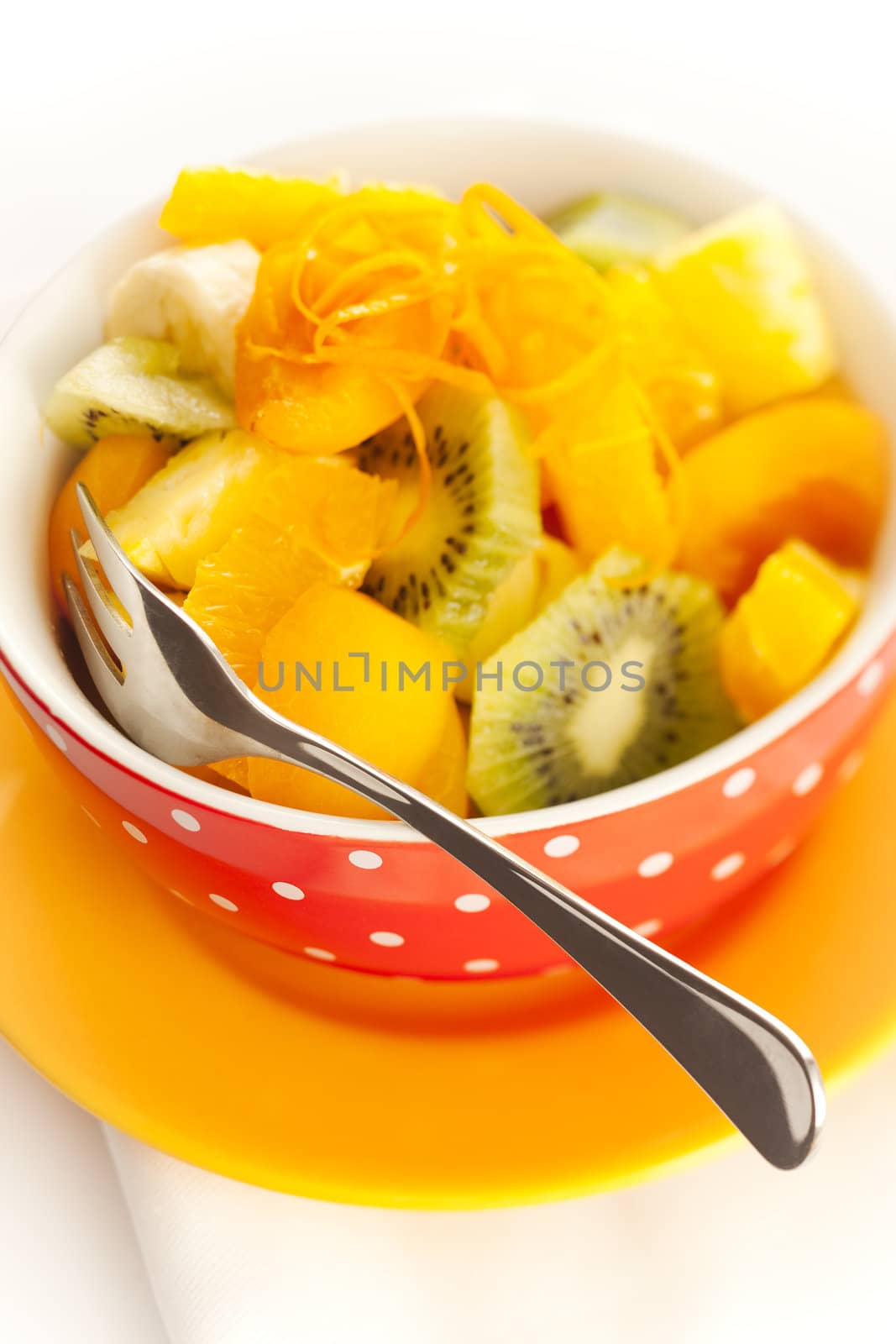 Fruit salad on the white dotted bowl (kiwi, orange, pinapple, banana etc).