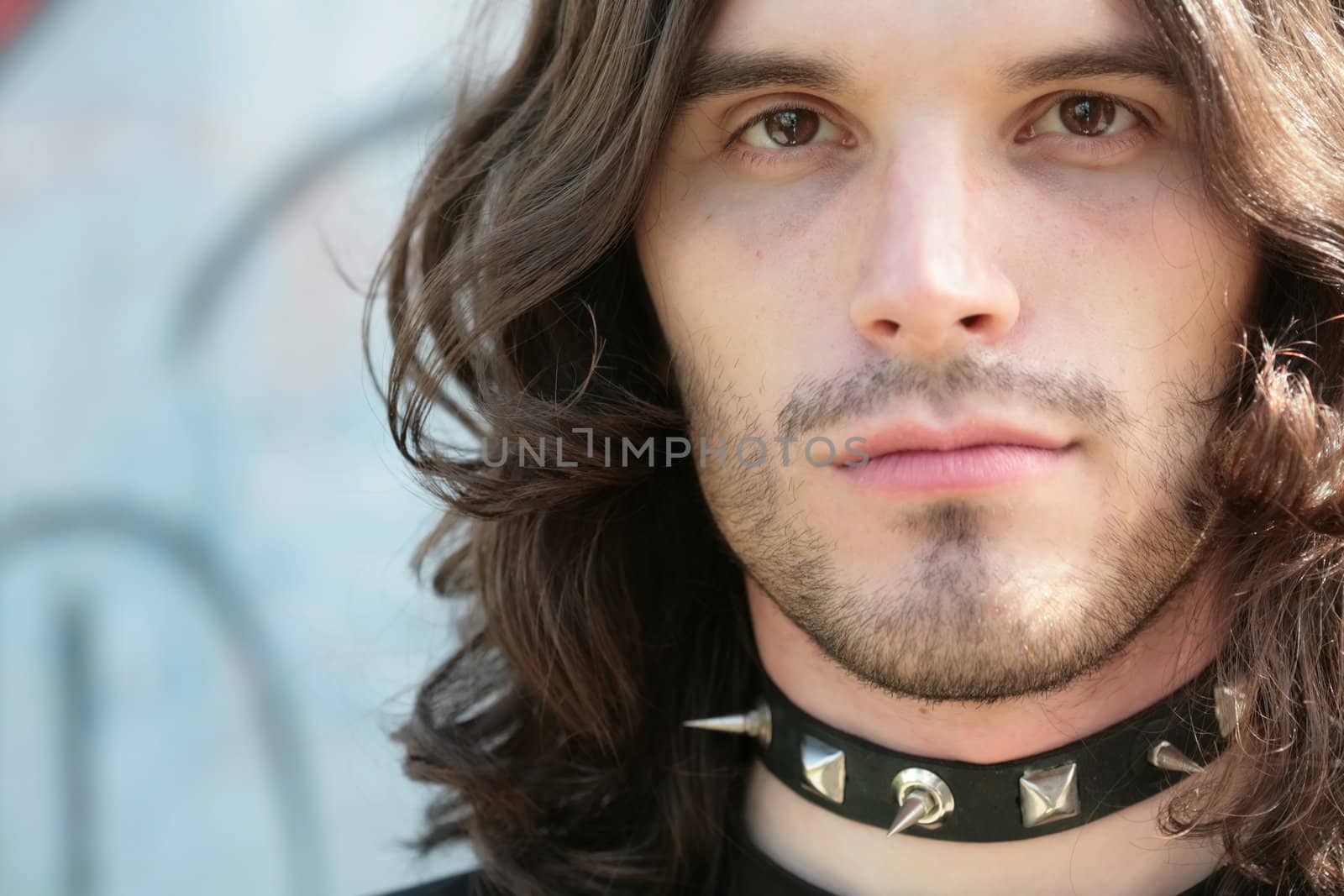 close-up portrait of the young man in gothic style in dog-collar with thorn and with copy-space