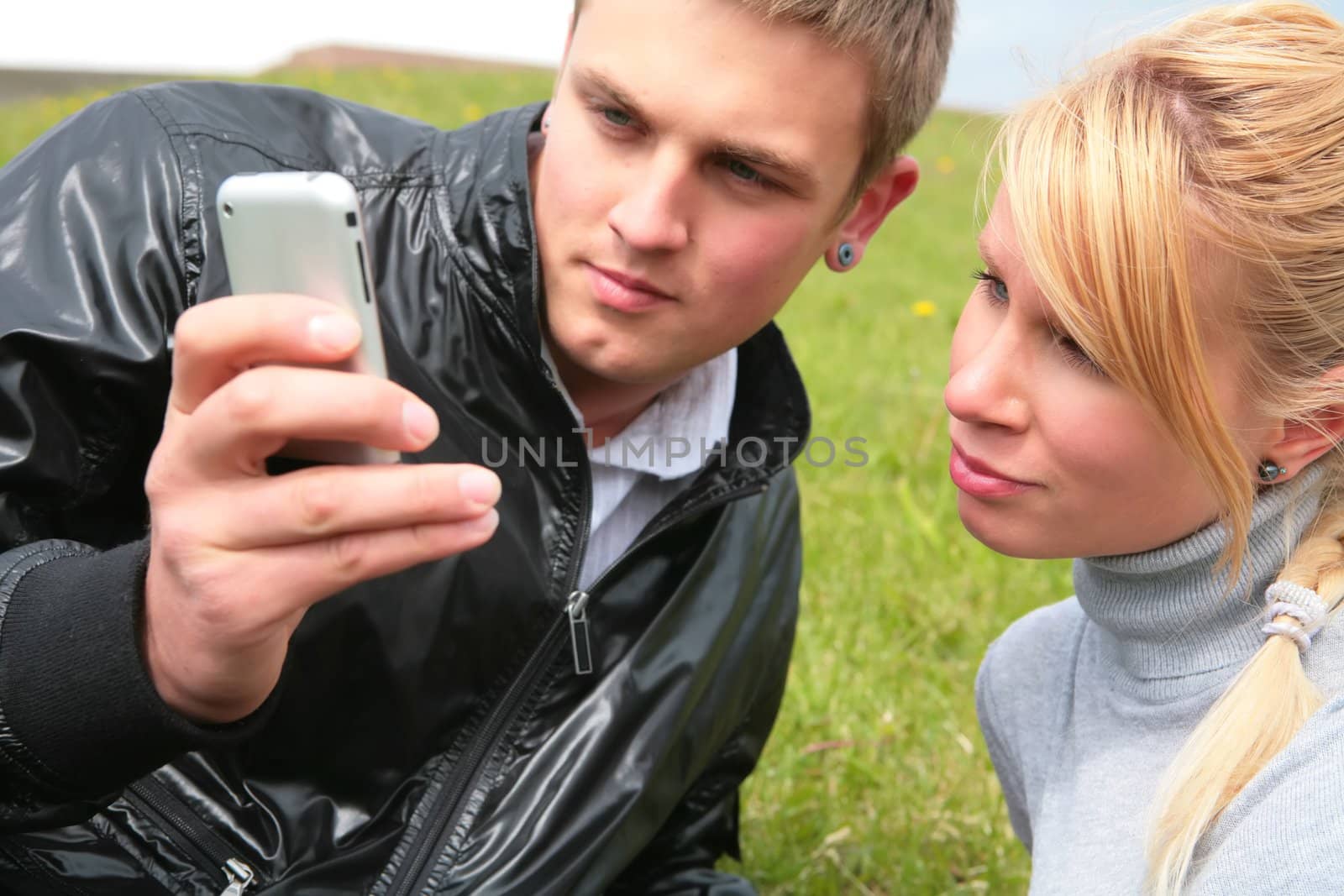 gay in black jacket and blond girl look at device