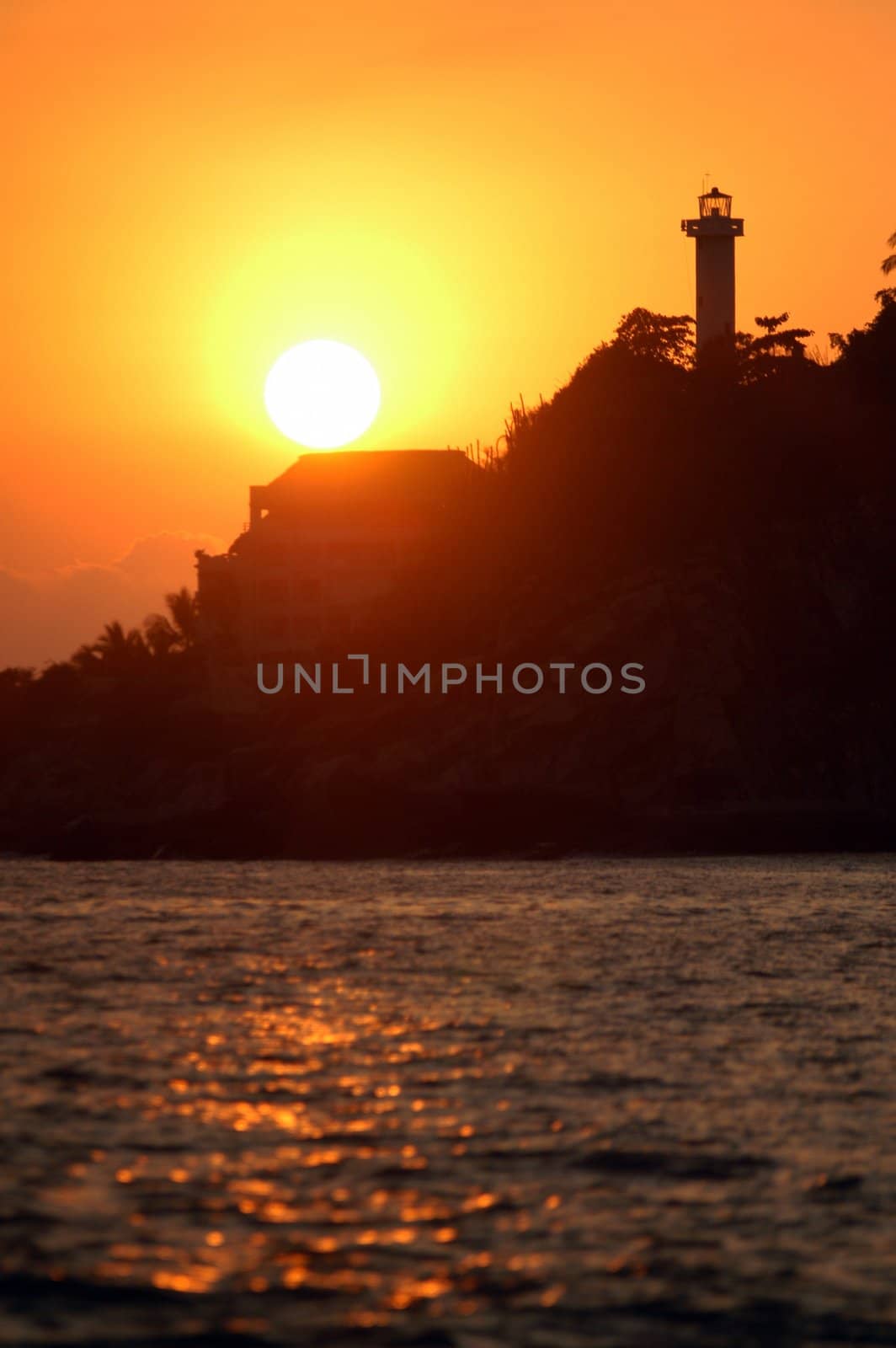 Silhouette of lighthouse and palms during sunset over the beach of Puerto Escondido