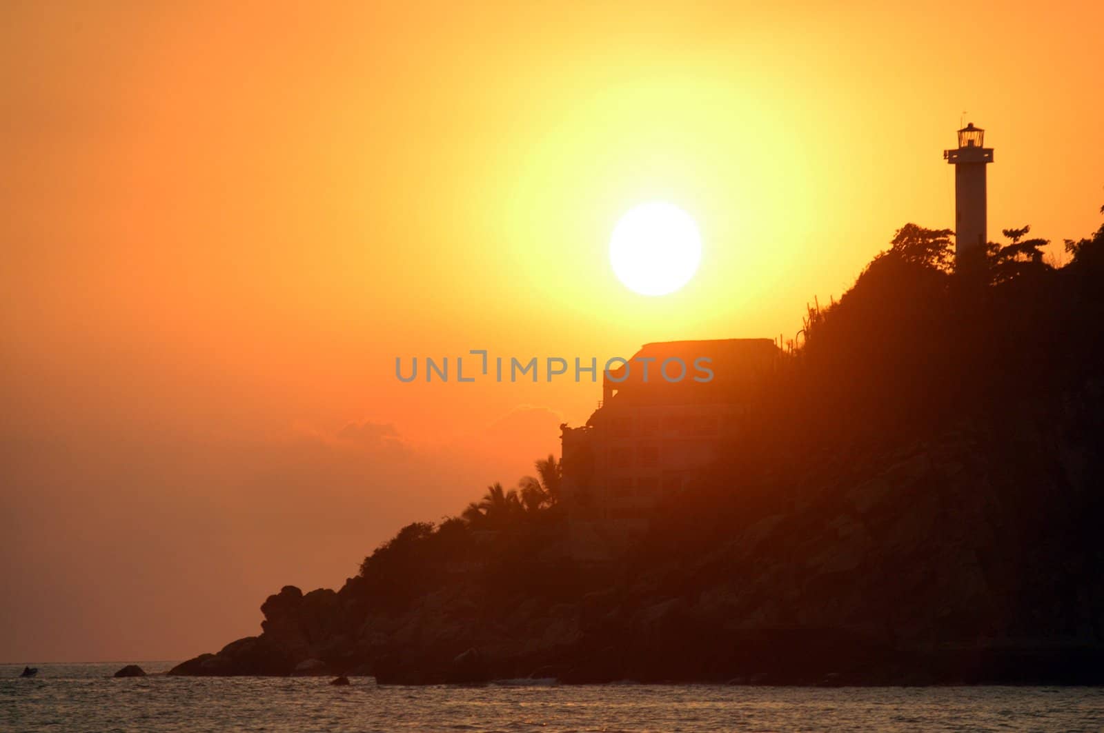 Silhouette of lighthouse and palms during sunset over the beach of Puerto Escondido