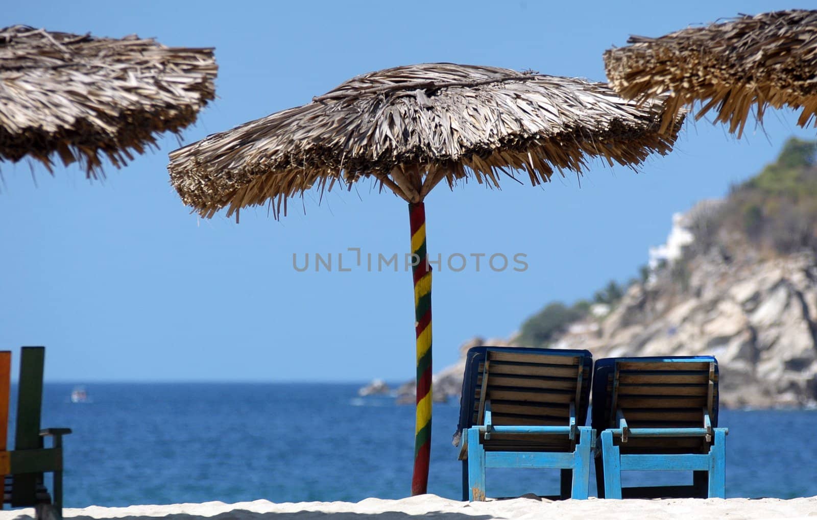 Strawy ubrellas and  deck chairs on the beach in Puerto Escondido, Mexico