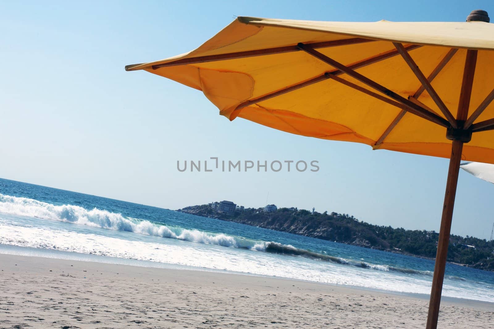 Yellow beach umbrella on beach in Puerto Escondido, Mexico